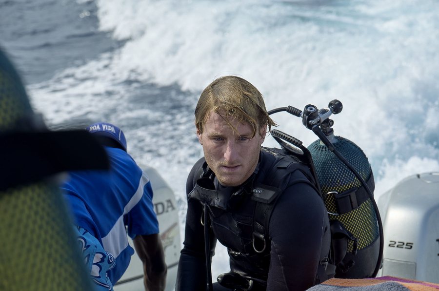 A diver kitted up on a speeding dive boat