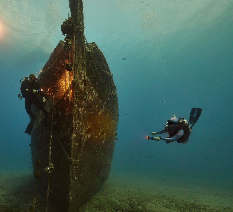 A diver lighting the bow of a shipwreck