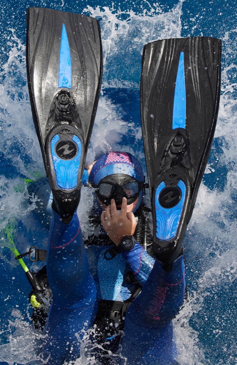 A diver on the surface in white water, fins up, seen from above