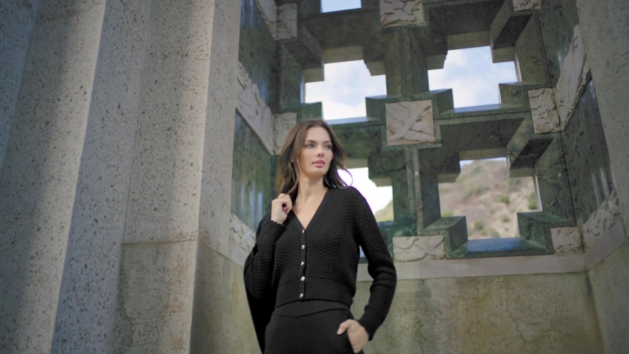 A woman in a black knit set against carved stone and sky