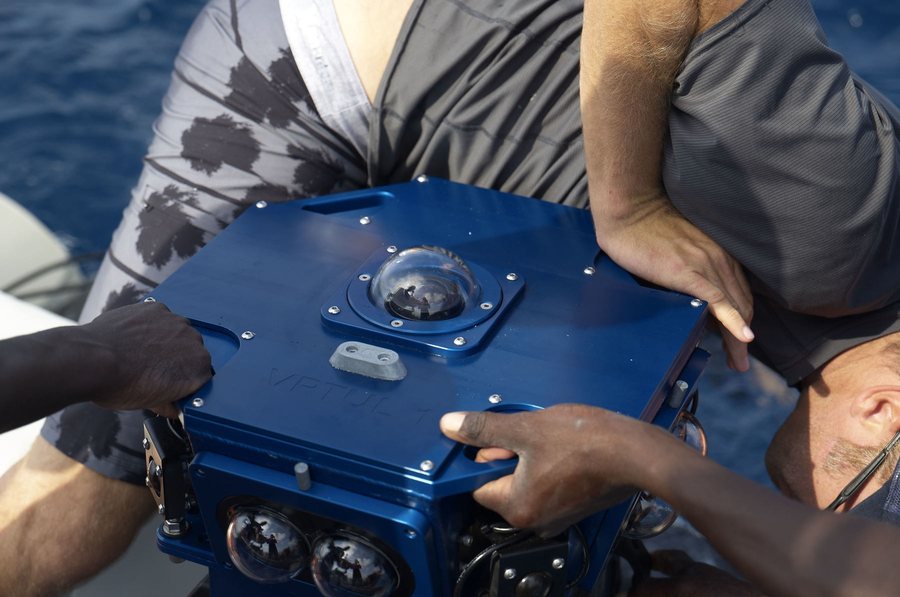 Crew lifting the multi-camera VR housing on the boat