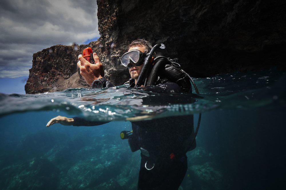 Half above, half below the waterline: a diver at a rocky shore