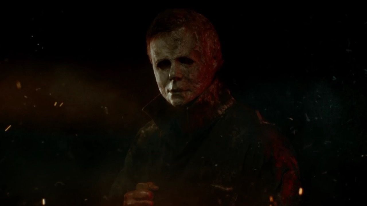 Halloween Ends: the masked figure standing in drifting embers and smoke