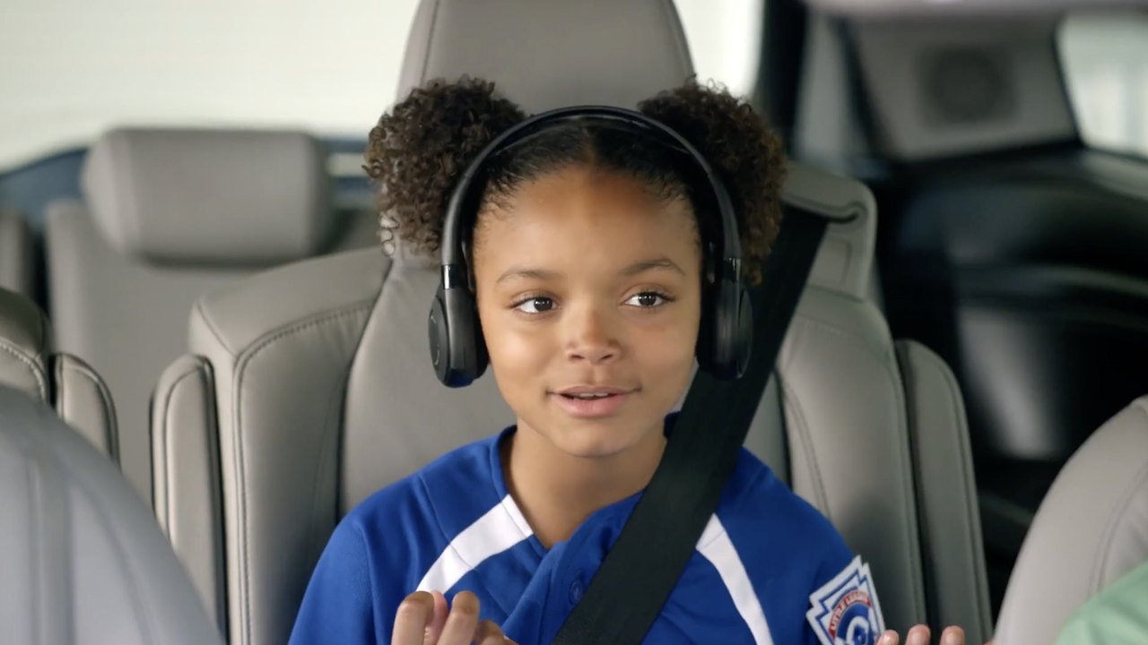 Honda and Little League: a girl in a team jersey and headphones in the back seat