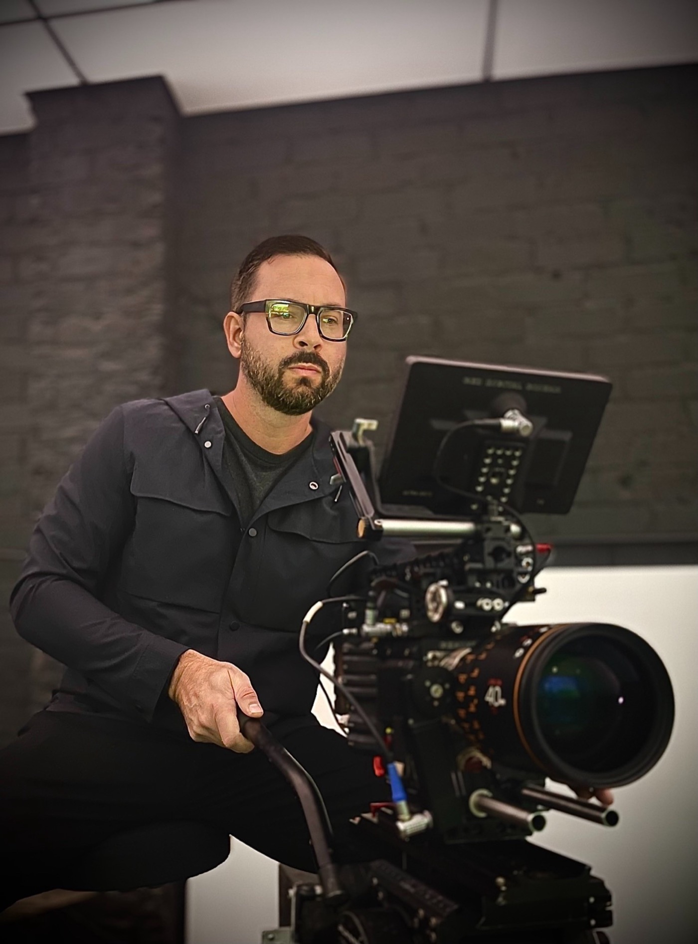 Jeffrey at the eyepiece of a cinema camera in a studio