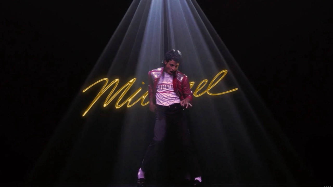 Michael: a performer in a spotlight on a dark stage, the film’s gold script title behind him