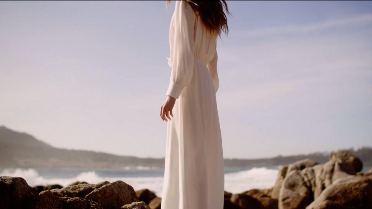 Morning Light for Brochu Walker: a woman in white on coastal rocks