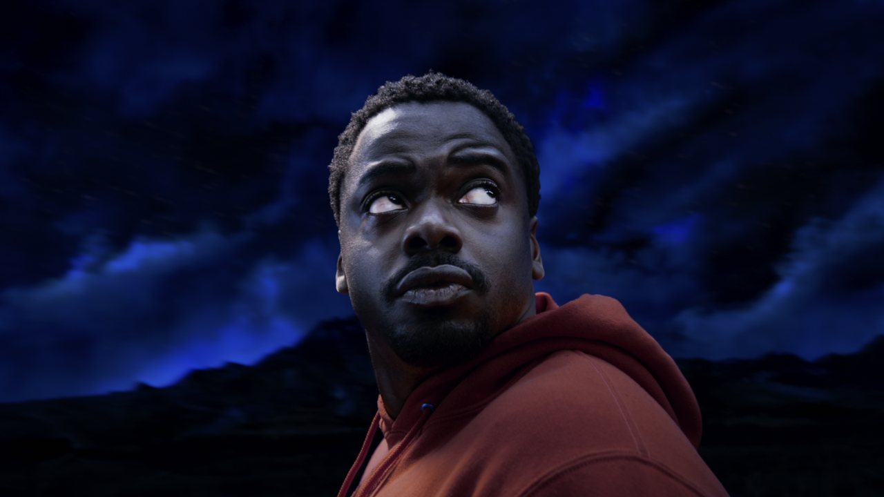 NOPE promo: a man in a red hoodie under an electric-blue night sky