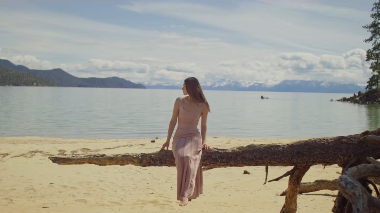 St. John at Lake Tahoe: a woman in a pale gown walking a fallen log on the shore